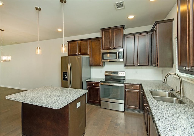 kitchen featuring stainless steel appliances, dark hardwood / wood-style floors, tasteful backsplash, sink, and a center island