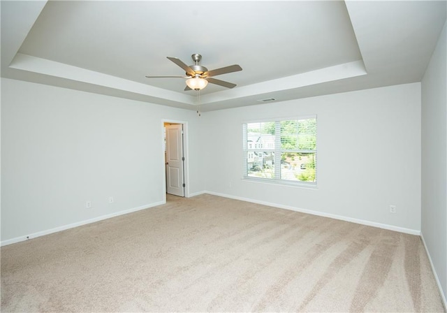 carpeted empty room with a tray ceiling and ceiling fan