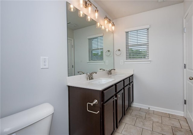 bathroom featuring tile patterned floors, double vanity, and toilet