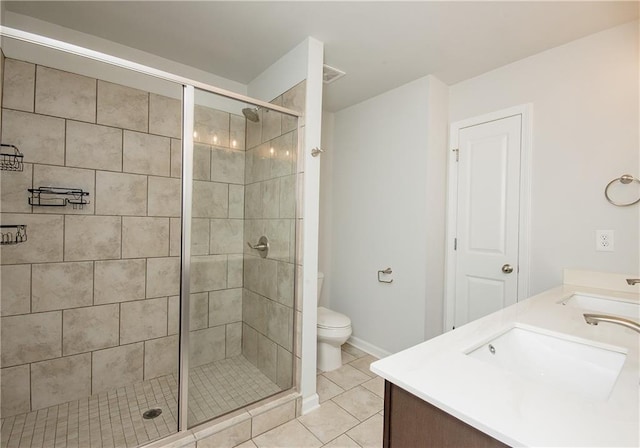 bathroom with tile patterned floors, dual bowl vanity, a shower with door, and toilet