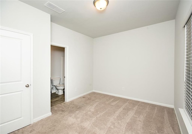 unfurnished bedroom featuring connected bathroom and light colored carpet