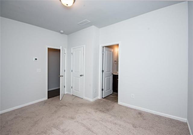 unfurnished bedroom with ensuite bath and light carpet