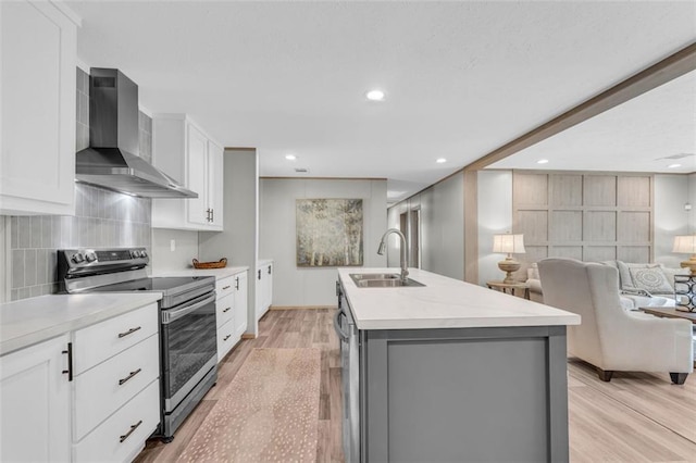 551 Fern Valley Trl, Clarkesville, GA 30523 - kitchen with wall chimney exhaust hood, electric range, a sink, light wood-style floors, and an island with sink