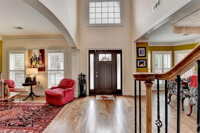 foyer with crown molding, stairs, visible vents, and wood finished floors