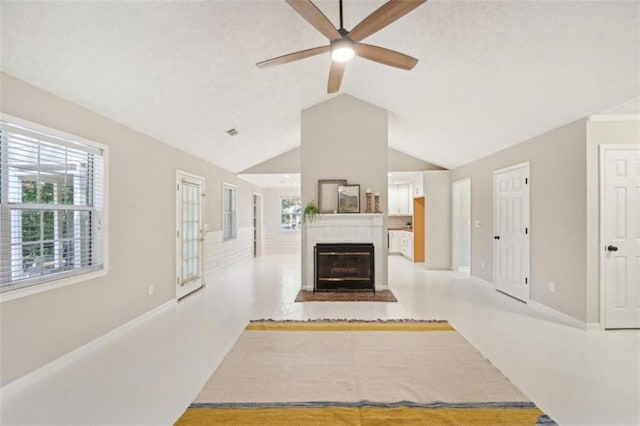 unfurnished living room with ceiling fan, a tile fireplace, and lofted ceiling