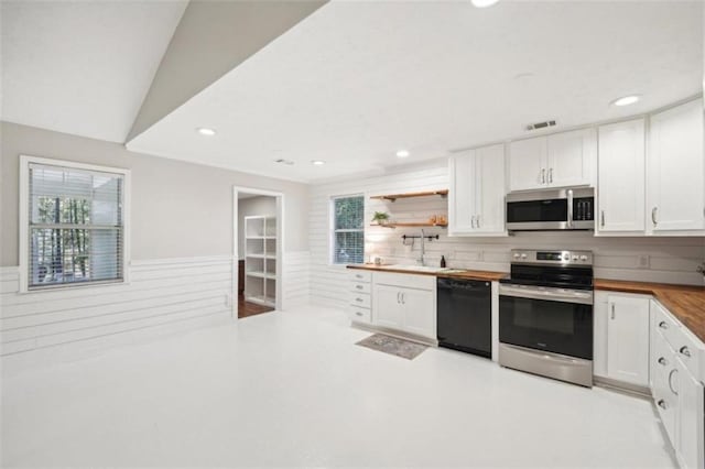 kitchen featuring appliances with stainless steel finishes, lofted ceiling, wood counters, white cabinetry, and sink