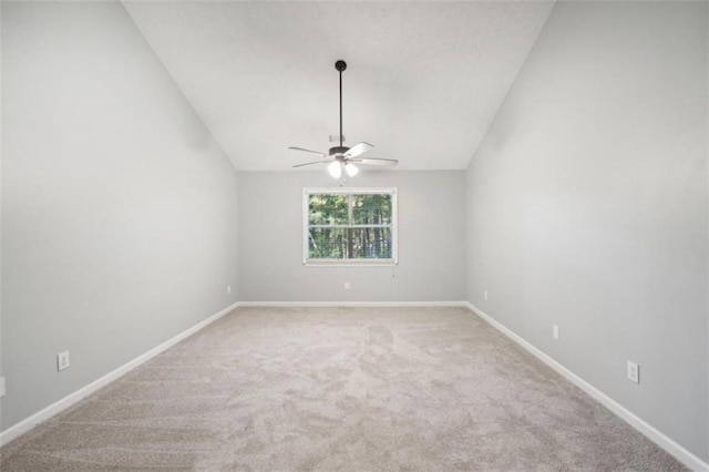 carpeted spare room featuring vaulted ceiling and ceiling fan