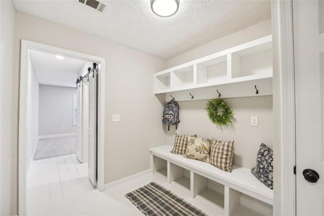 mudroom with a barn door and a textured ceiling