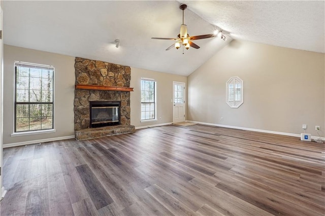 unfurnished living room featuring high vaulted ceiling, a textured ceiling, dark hardwood / wood-style floors, ceiling fan, and a fireplace