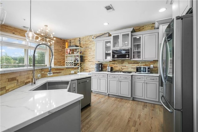1165 Laurel Pl SE, Smyrna, GA 30080 - kitchen with appliances with stainless steel finishes, decorative backsplash, decorative light fixtures, light wood-style floors, and glass insert cabinets