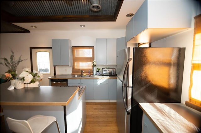 kitchen featuring appliances with stainless steel finishes, light hardwood / wood-style floors, sink, and gray cabinetry