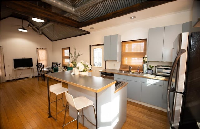 kitchen featuring stainless steel appliances, sink, a breakfast bar, and light hardwood / wood-style flooring