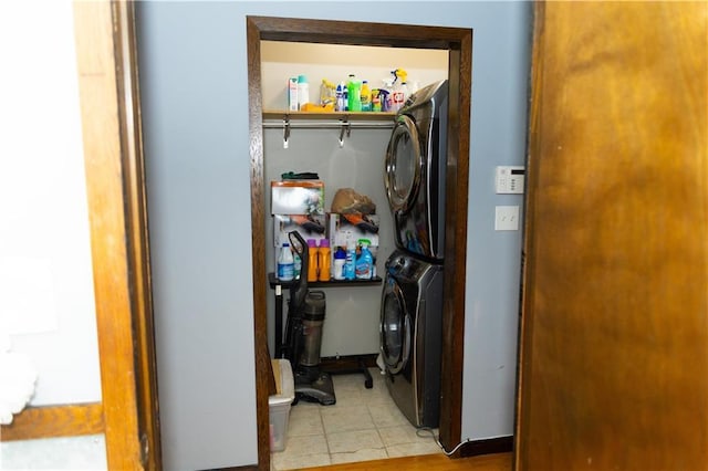 laundry room featuring stacked washer / drying machine and light tile patterned floors