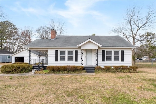 view of front of property with a garage, a front lawn, and a chimney