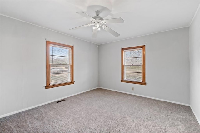 carpeted spare room featuring ceiling fan, baseboards, visible vents, and a healthy amount of sunlight