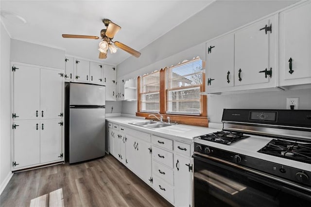 kitchen featuring range with gas stovetop, light countertops, freestanding refrigerator, white cabinets, and a sink