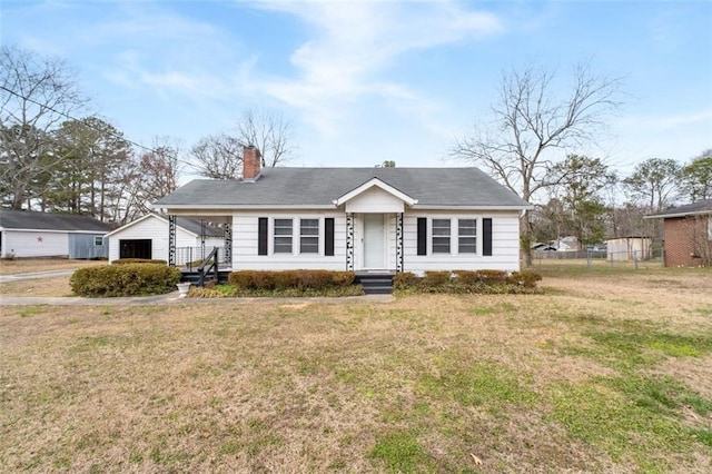 view of front of property featuring a chimney, fence, a front lawn, and an outdoor structure