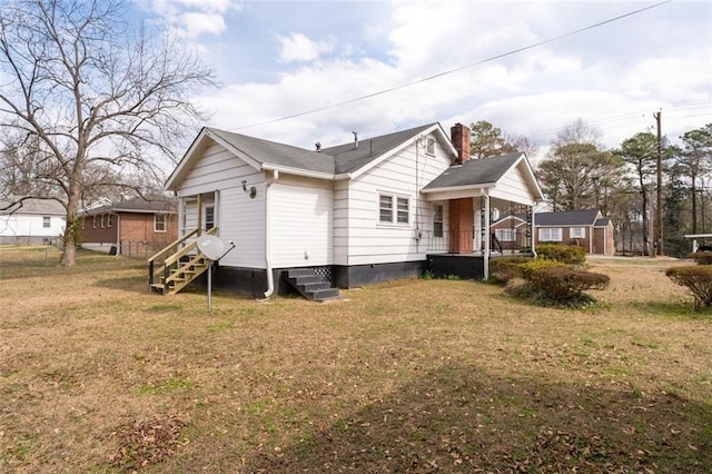 back of property with entry steps, a lawn, and a chimney