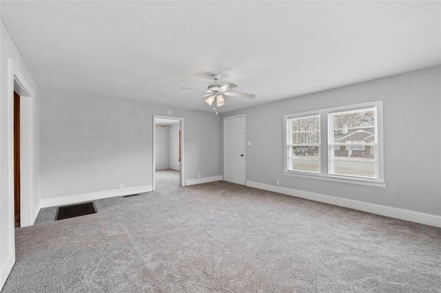 carpeted empty room with ceiling fan and baseboards