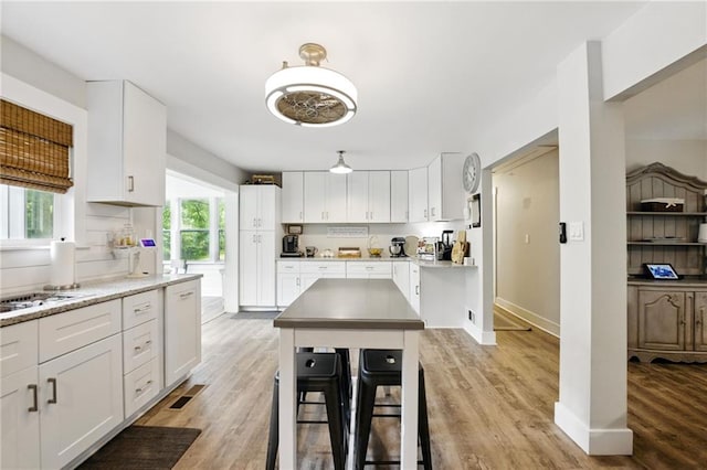 kitchen with light wood finished floors, white cabinetry, baseboards, and a center island