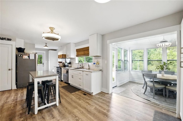kitchen featuring a sink, appliances with stainless steel finishes, white cabinets, wood finished floors, and baseboards