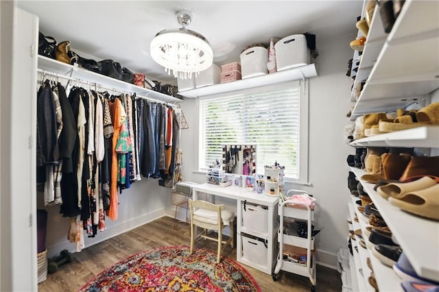 walk in closet with wood finished floors and a chandelier