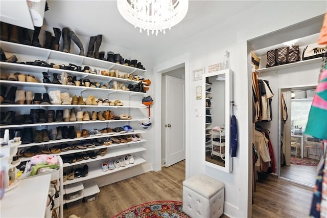 spacious closet featuring wood finished floors and a chandelier