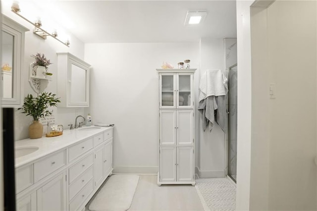 full bathroom with baseboards, a shower stall, and double vanity