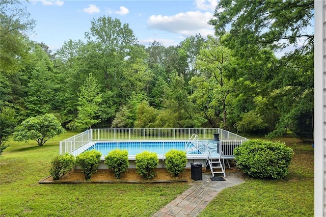 view of swimming pool with a lawn and a view of trees