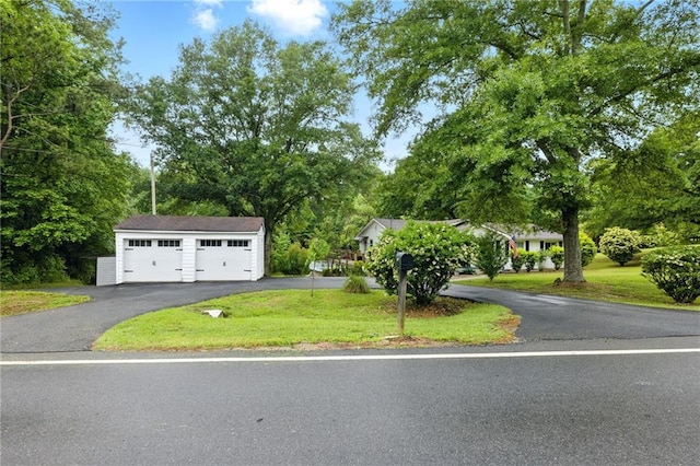 view of front facade featuring a front lawn, a detached garage, and view of scattered trees