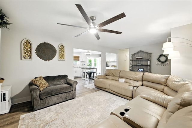 living area with ceiling fan, wood finished floors, and baseboards