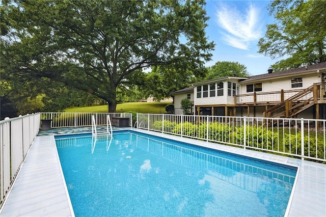 outdoor pool featuring fence, stairway, and a deck