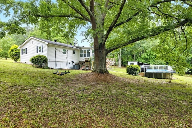 view of green lawn featuring an outdoor pool, an outdoor structure, and a deck