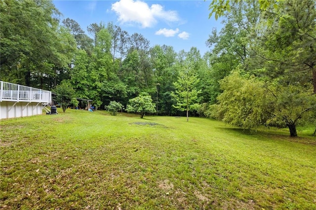 view of grassy yard with a forest view