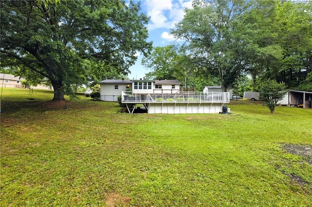 view of grassy yard with an outdoor pool and a wooden deck
