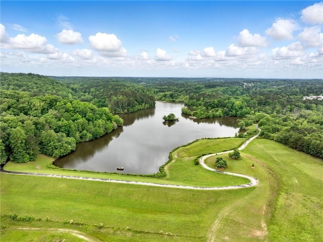 drone / aerial view of a nearby body of water and a heavily wooded area
