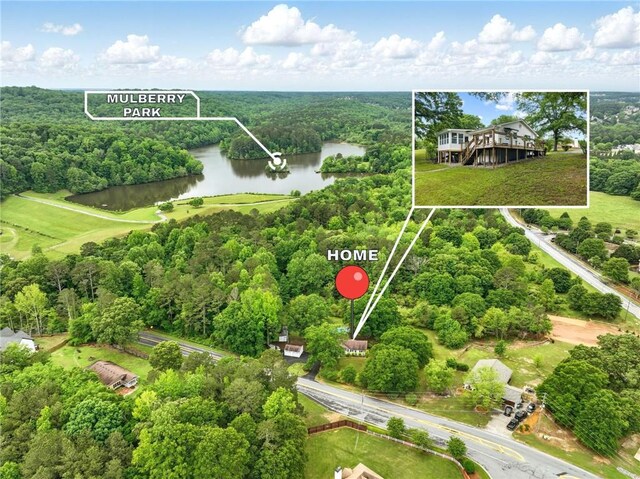 drone / aerial view of a nearby body of water and a forest