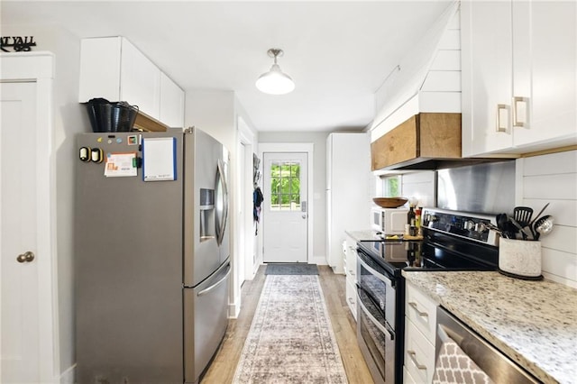 kitchen with appliances with stainless steel finishes, light wood-style floors, white cabinets, light stone counters, and baseboards
