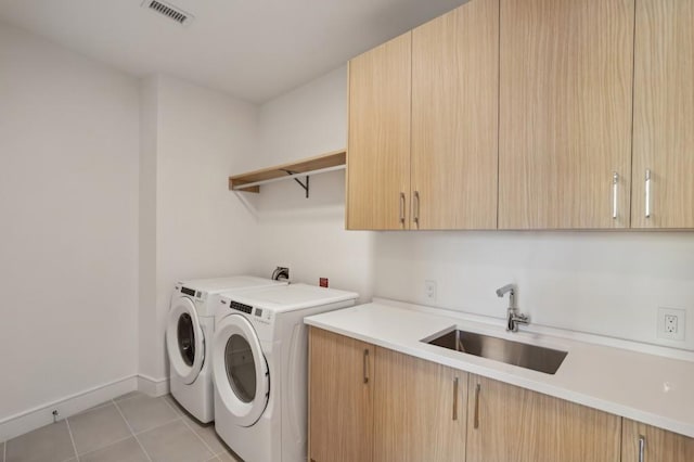 laundry area with washing machine and dryer, sink, light tile patterned floors, and cabinets