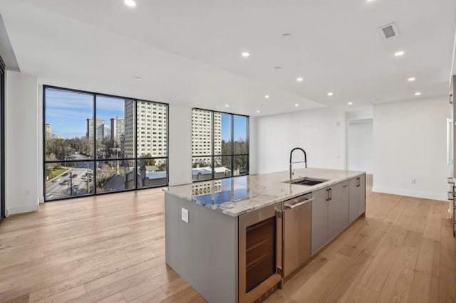 kitchen featuring gray cabinetry, light hardwood / wood-style flooring, a large island, and sink