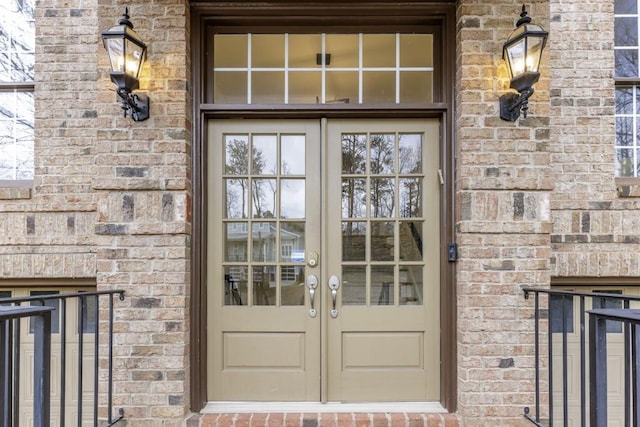 view of exterior entry featuring french doors and brick siding