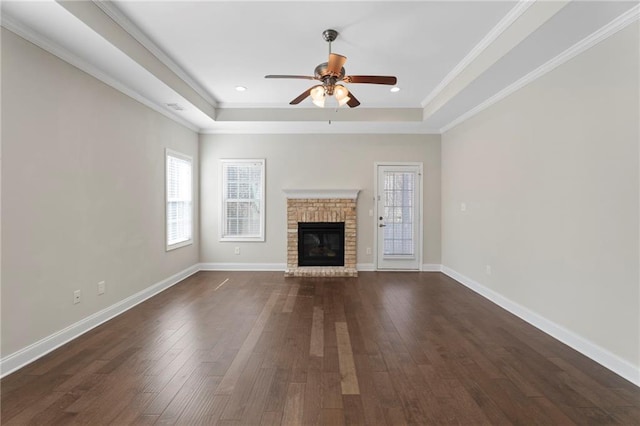 unfurnished living room featuring a tray ceiling, a wealth of natural light, and dark wood-type flooring