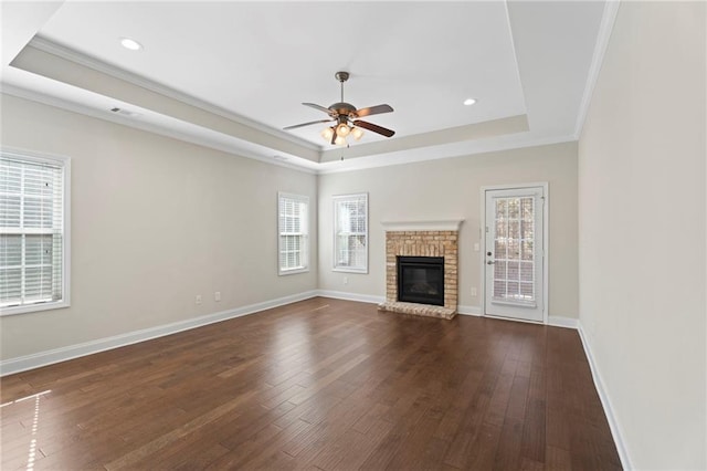 unfurnished living room featuring dark hardwood / wood-style flooring, crown molding, a fireplace, and a raised ceiling