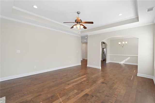 unfurnished room featuring crown molding, dark wood-type flooring, ceiling fan with notable chandelier, and a tray ceiling