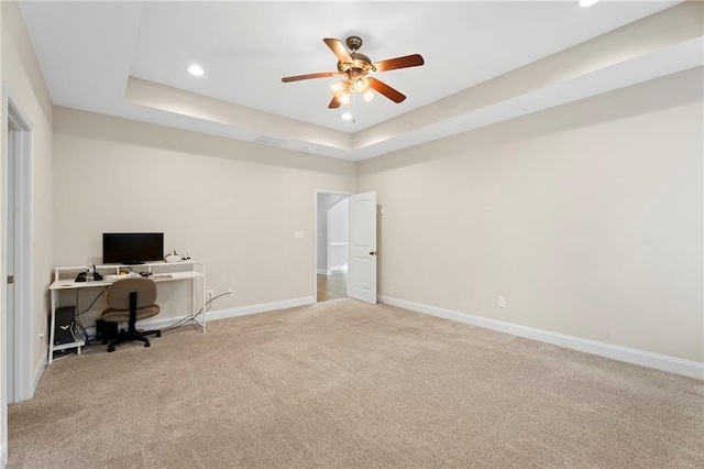 unfurnished office with a raised ceiling, carpet, and ceiling fan