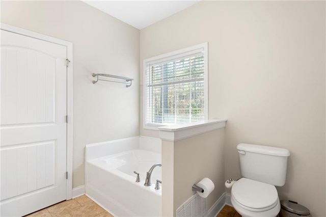 bathroom with a washtub, tile patterned flooring, and toilet