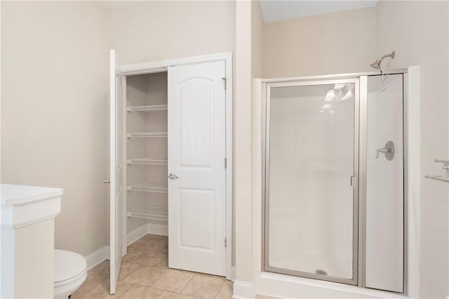 bathroom with tile patterned floors, toilet, and a shower with shower door