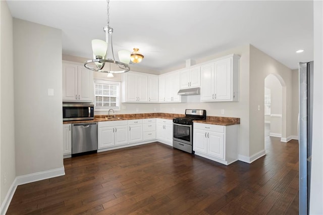 kitchen featuring sink, dark wood-type flooring, appliances with stainless steel finishes, white cabinets, and decorative light fixtures