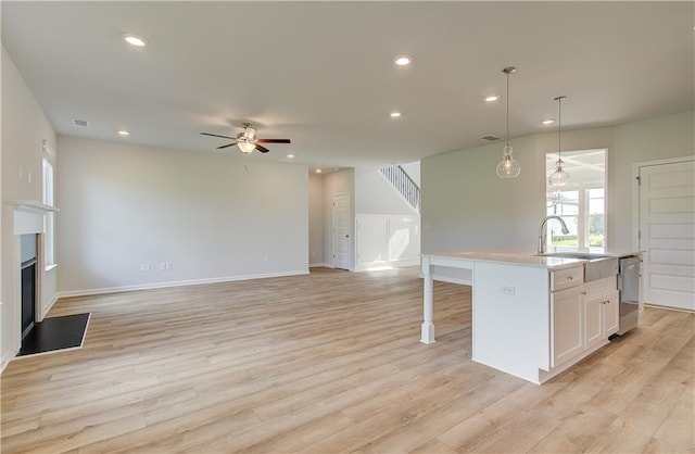 kitchen featuring white cabinets, light wood-type flooring, a kitchen island with sink, and ceiling fan