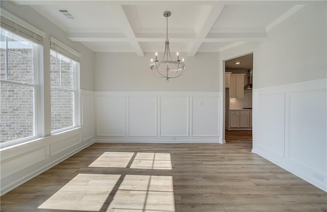 unfurnished dining area with beamed ceiling, a notable chandelier, coffered ceiling, and light hardwood / wood-style flooring